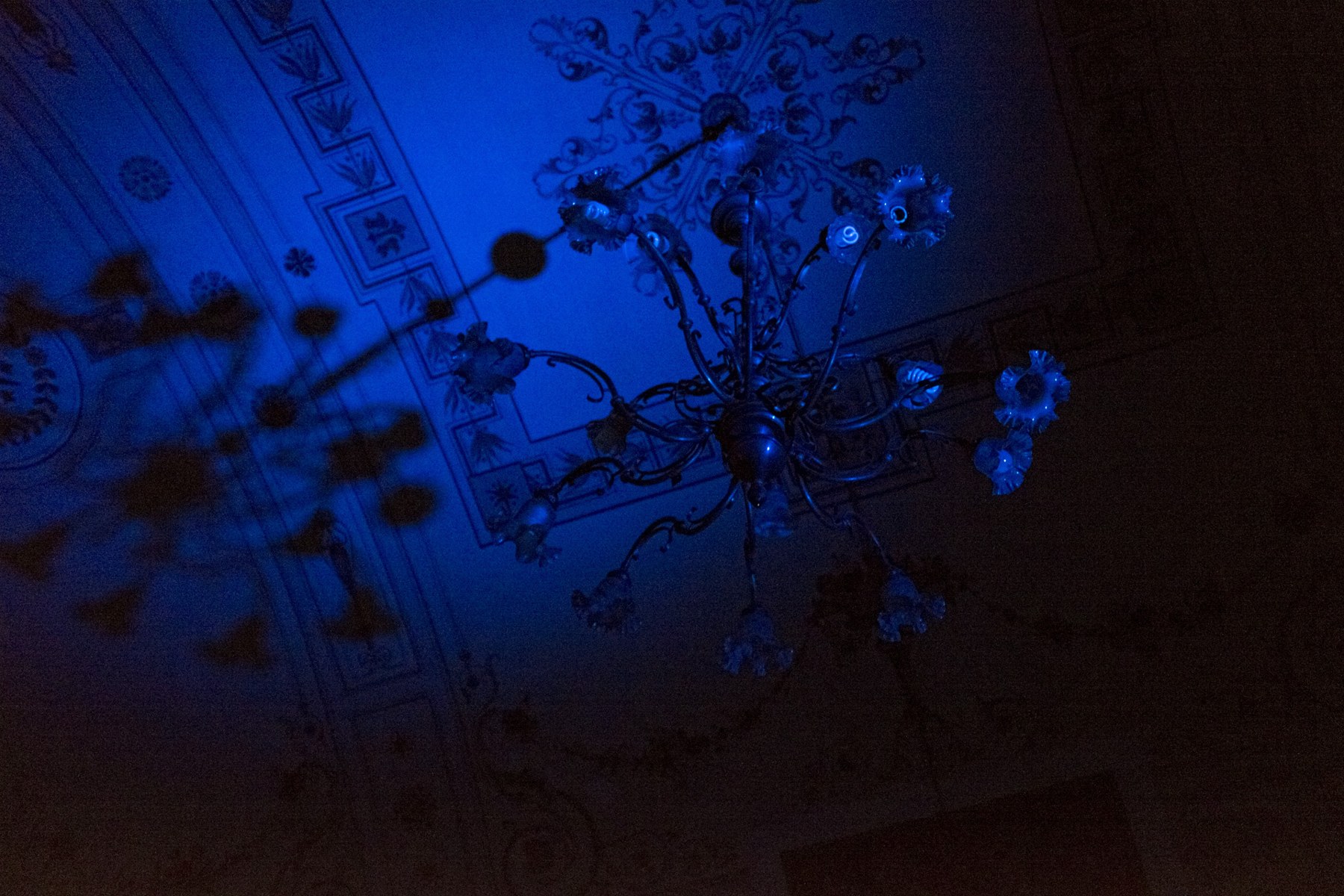 Original dark chandelier under intense blue lighting